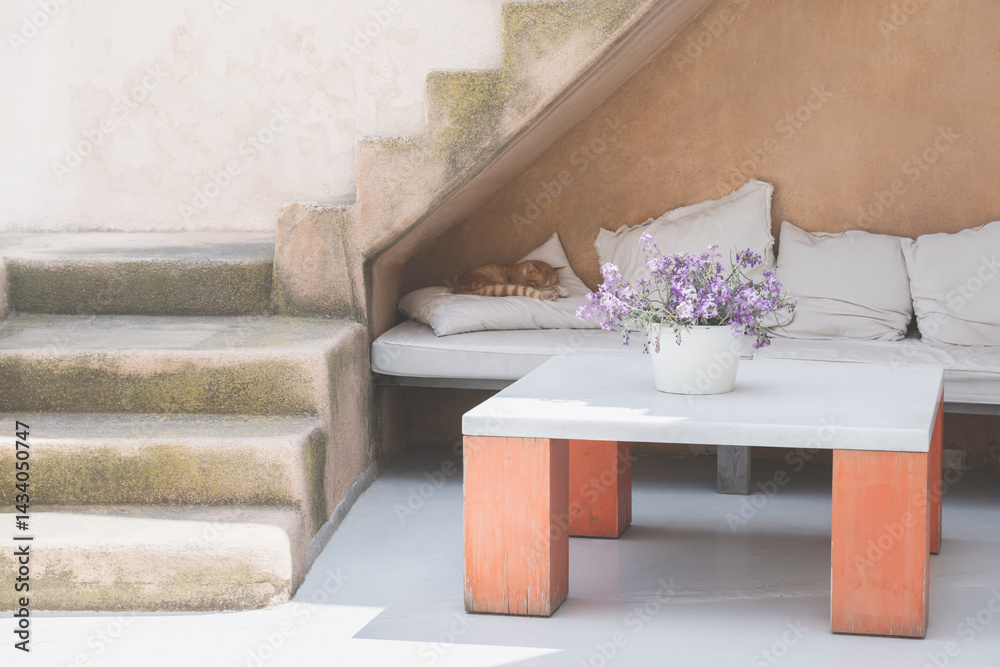 White cycladic architecture in Santorini island, Greece. Cozy terrace of the house. Cat is sleeping on the sofa