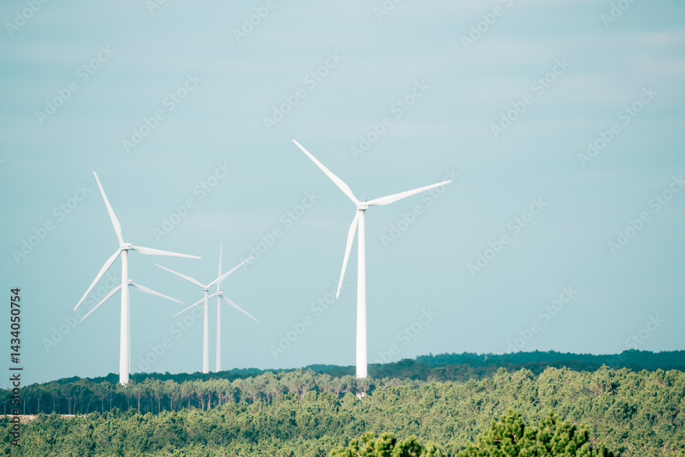 Wind turbines on the hills with green trees against the blue sky. Nature, ecology and technology concept