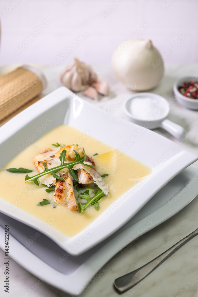 Creamy potato soup with grilled chicken, parmesan flakes and arugula, ingredients on light background