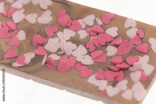 Obraz na płótnie Milk chocolate bar covered with small pink and white sugar hearts w salonie