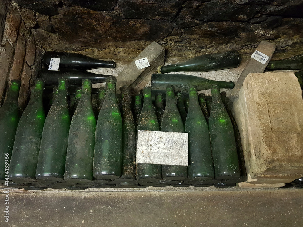 Dusty wine bottles aging in a dark cellar