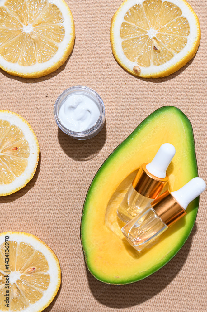 Two transparent skincare dropper bottles with golden caps placed inside a fresh avocado half, surrounded by green leaves on textured beige background. Natural beauty and organic skincare concept