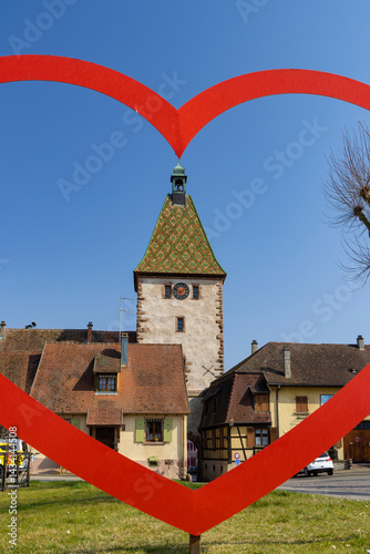 Big red heart framing medieval tower in turckheim, alsace, france