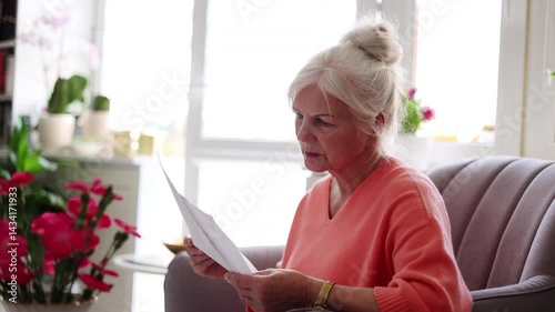 Senior woman looking through financial documents at home 
