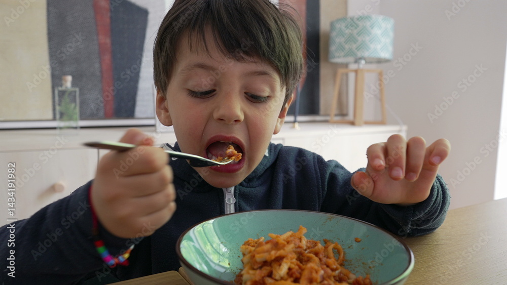 Child twirling spaghetti with a fork, gripping it tightly while intensely focused on the meal, highlighting the effort and engagement in self-feeding within a familiar home environment-SD 480p Child twirling spaghetti with a fork, gripping it tightly while intensely focused on the meal, highlighting the effort and engagement in self-feeding within a familiar home environment-SD 480p