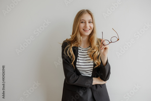 Young woman with glasses smiling confidently in a modern office setting during daylight hours