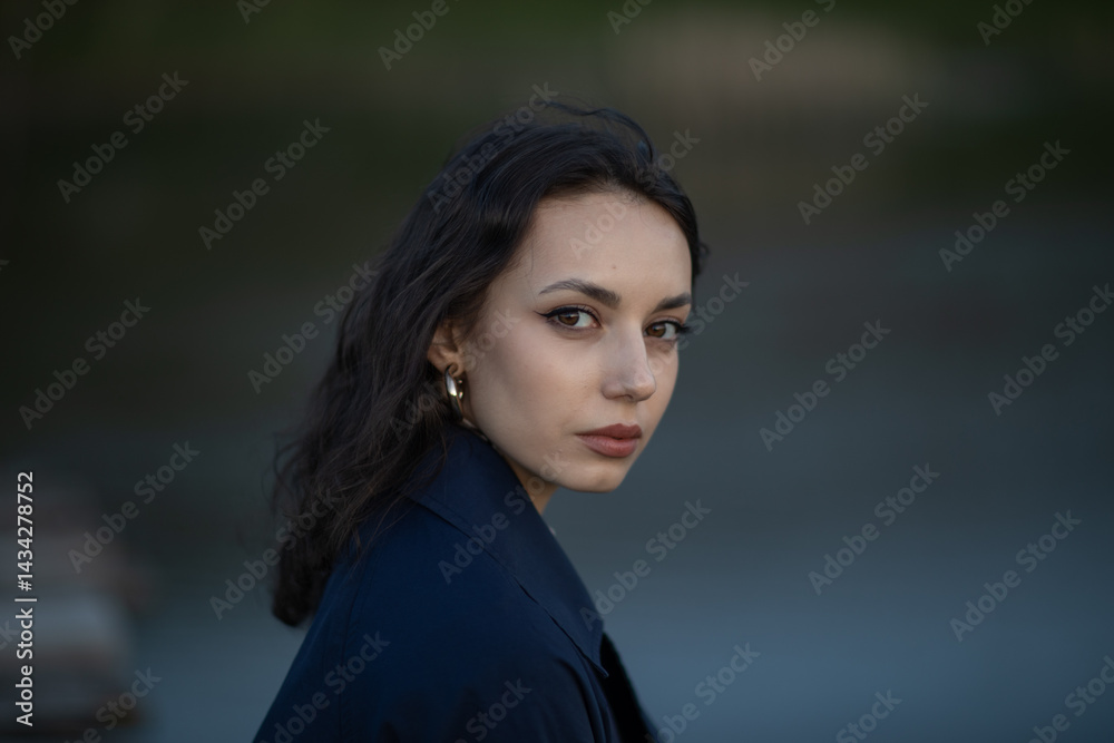 Beautiful brunette meditates sadly in the park in the evening light. Sad girl