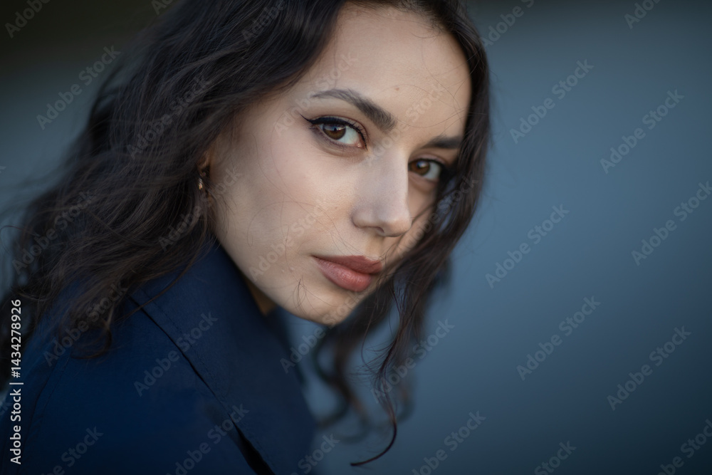 Portrait of a beautiful Asian woman with long black hair and wearing blue coat.