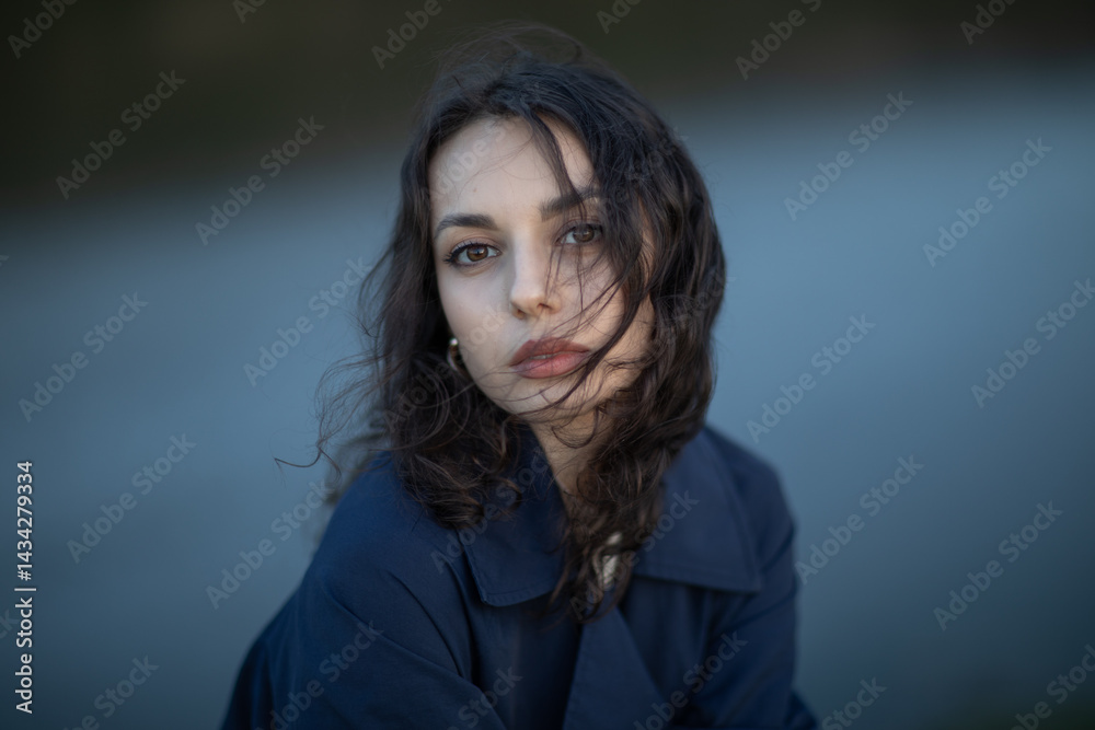 Portrait of a beautiful Asian woman with long black hair and wearing blue coat.