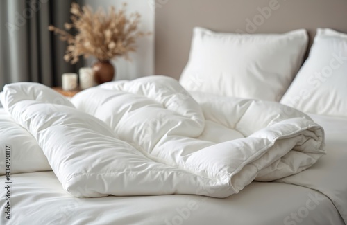 White soft duvet with pillows, white bedclothes, preparation for winter season. Warm home textiles, cozy rest. Home interior, comfort. Bedchamber background, household chores.