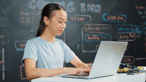 Obraz na płótnie Smart girl programing system by using laptop at blackboard. Highschool student writing engineering code or prompt while looking at screen at STEM technology class. Creative education. Edification. w salonie