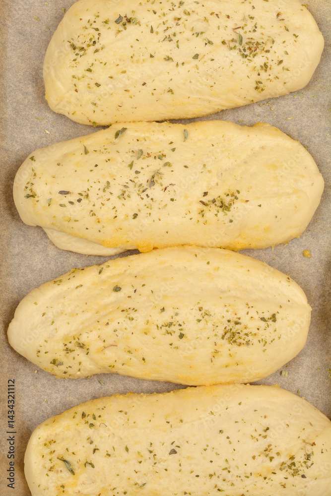 A close-up shows several golden-brown bread rolls seasoned with garlic and oregano, suggesting a flavorful and aromatic baked good