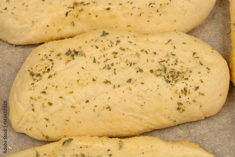 A close-up shows several golden-brown bread rolls seasoned with garlic and oregano, suggesting a flavorful and aromatic baked good
