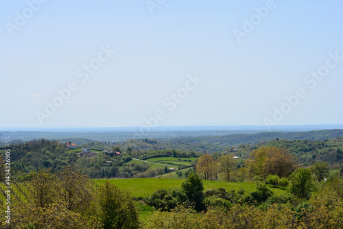 Obraz na płótnie Gornje PsarjevoA picturesque view from Gornje Psarjevo in Croatia extends eastward over lush green fields and scattered houses under a clear sky w salonie