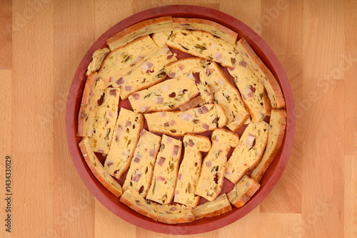 Obraz na płótnie A top-down view shows slices of prisnac, a savory egg, bacon and cheese pie, arranged in a round silicone mold on a light brown wooden surface w salonie