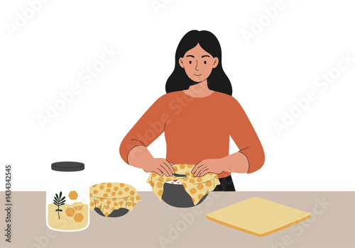 A young woman wraps a bowl with beeswax food wraps. She's smiling, wearing a long-sleeved orange shirt. Natural, sustainable food storage concept.