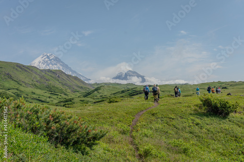 group of people walking along a dirt road towards a volcano