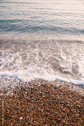 Gentle waves softly lapping on a pebbly beach at sunset hours