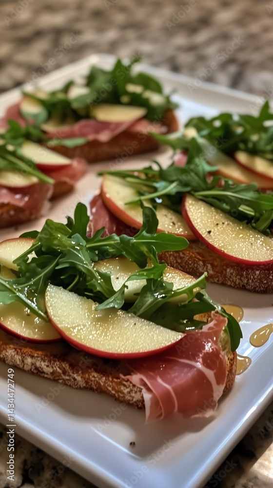 Delicious Open-Faced Sandwich With Prosciutto, Apples, and Arugula on a White Platter
