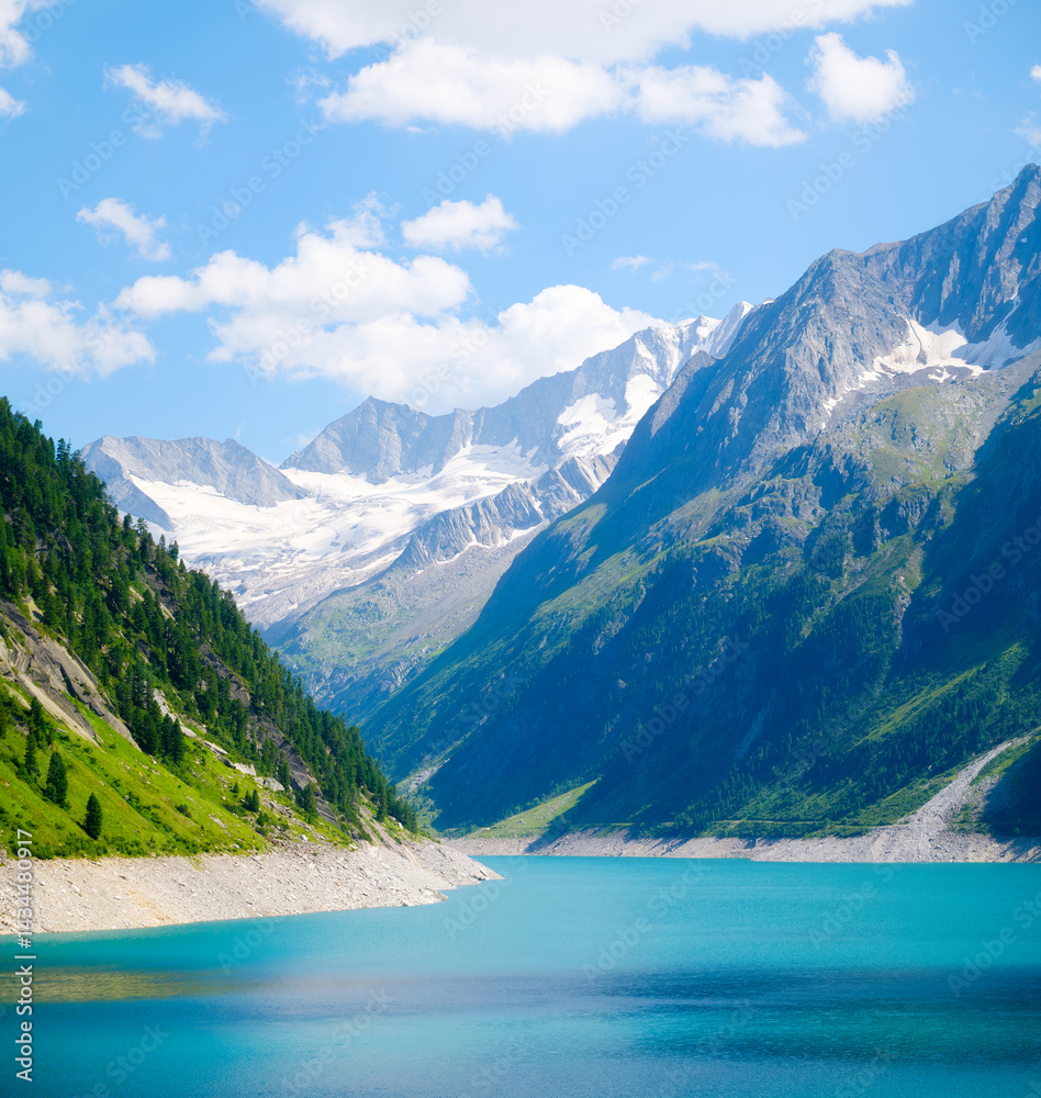 Azure lake and high mountain range in Austria. Mountain landscapes during summer. Warm sunny weather and clear skies. Place for mountain hiking, travel and vacation. Wallpaper, postcard, photo.