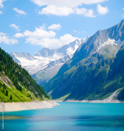 Obraz na płótnie Azure lake and high mountain range in Austria. Mountain landscapes during summer. Warm sunny weather and clear skies. Place for mountain hiking, travel and vacation. Wallpaper, postcard, photo. w salonie