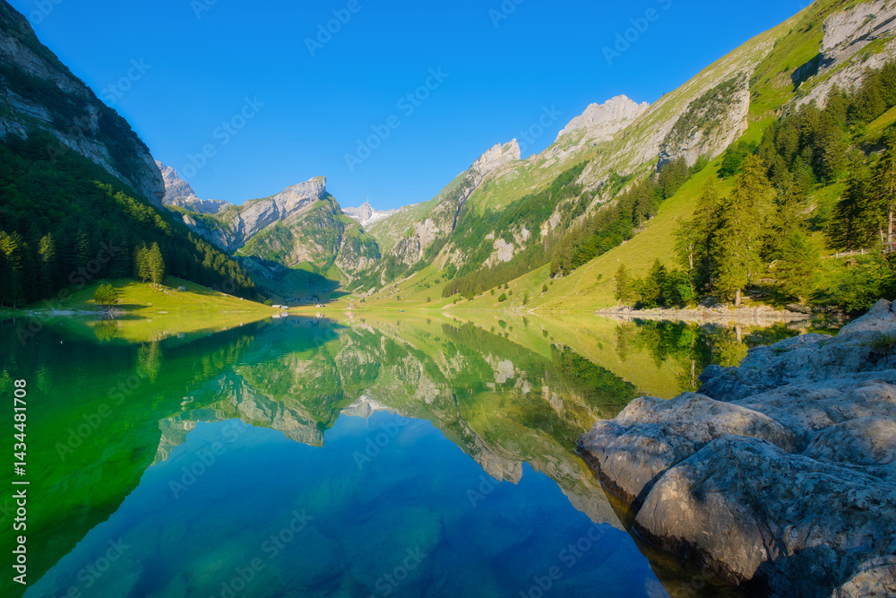 Seealpsee, Switzerland. Lake and reflections on the water surface. Mountain landscapes in summer. Place for mountain hiking, travel and vacation. Wallpaper, postcard, photo.