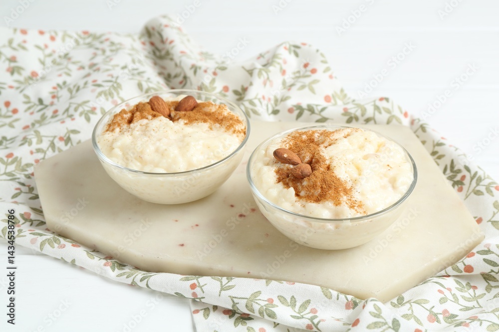 Delicious rice pudding with cinnamon and almonds in glass bowls on white table Delicious rice pudding with cinnamon and almonds in glass bowls on white table