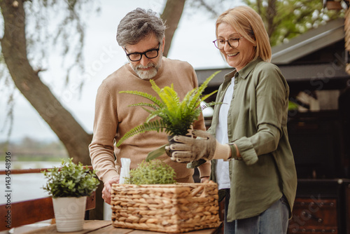 Wallpaper Mural Happy senior couple sorting and organize potted plants in front of home Torontodigital.ca