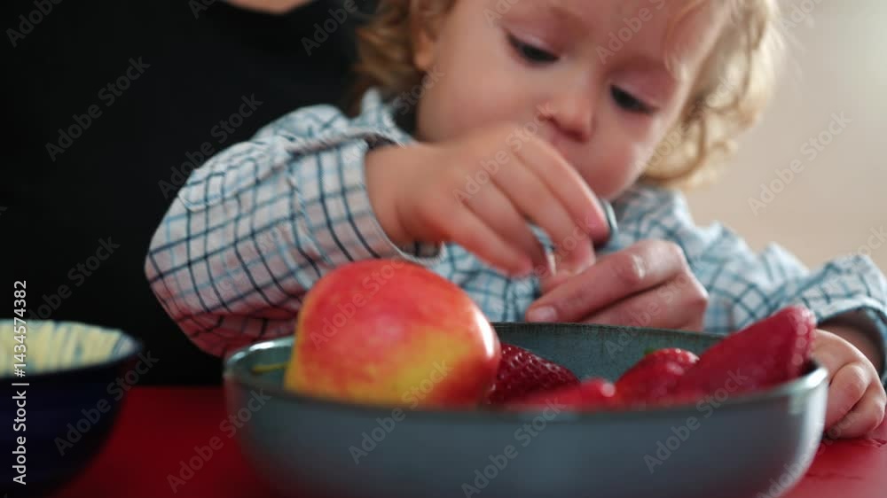 Child Reaches for Fresh Fruits While Dining With Parent at Table Child Reaches for Fresh Fruits While Dining With Parent at Table