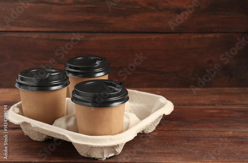Obraz na płótnie Paper coffee cups in cardboard holder on wooden table. Space for text w salonie