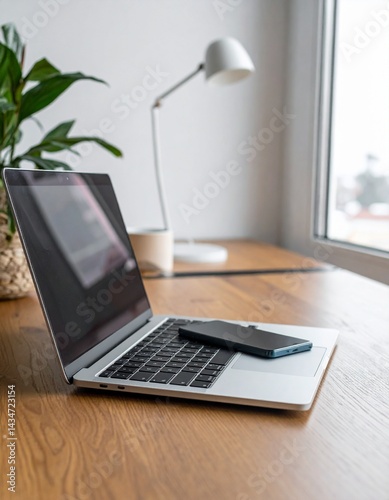 ノートパソコンとスマートフォンを並べたデスク上でのリモートワーク風景