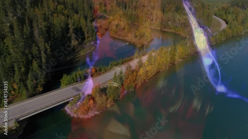 hand capturing winding road and bridge over lake via lens overlay, showcasing technology