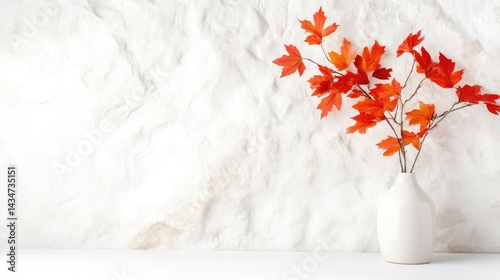 Autumnal maple leaves in a white vase against a textured white wall.