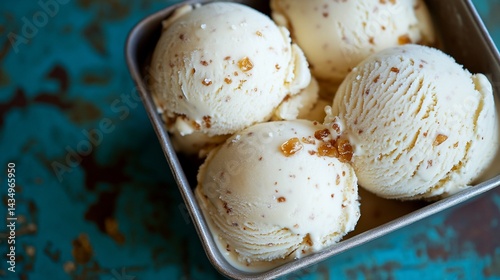 Obraz na płótnie Creamy, light-yellow ice cream scoops in a small metal tin, topped with crunchy bits w salonie