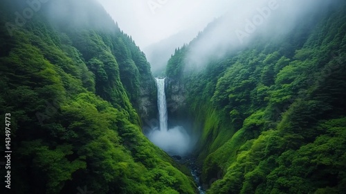 Majestic waterfall cascading down a lush, green valley, shrouded in mist. Verdant mountains surround the scene, creating a tranquil and serene atmosphere