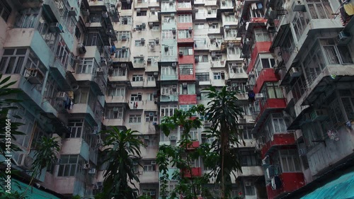 Explore the intricate design of Hong Kong's infamous monster building. A captivating view from the ground looking up, showcasing densely packed apartments, air conditioning units, and vibrant colors
