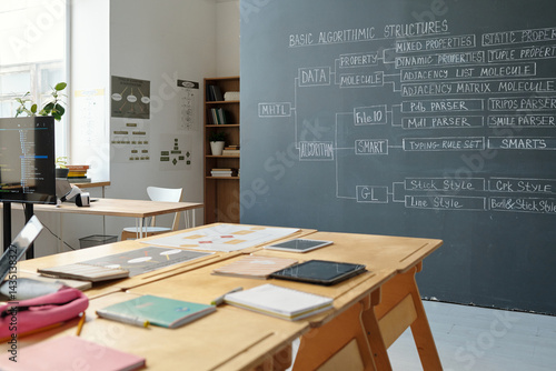 Organized modern office setup with digital devices on wooden desks and whiteboards displaying various diagrams and annotations Everybody is enjoying an educational or professional environment