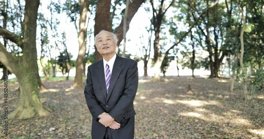 In a cold park in Japan in March, a man in his 70s, in a suit, stands and talks. Surrounded by crisp early spring air and peaceful nature, he shares his thoughts quietly in the calm surroundings. In a cold park in Japan in March, a man in his 70s, in a suit, stands and talks. Surrounded by crisp early spring air and peaceful nature, he shares his thoughts quietly in the calm surroundings.