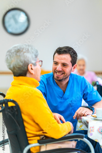 Male nurse comforting elderly woman in wheelchair at nursing home