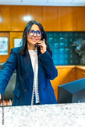 Obraz na płótnie Smiling receptionist answering phone at nursing home reception desk w salonie