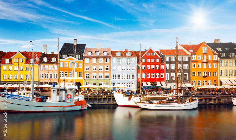 Naklejka premium Copenhagen colored building in Nyhavn with blue sky and sun, Denmark