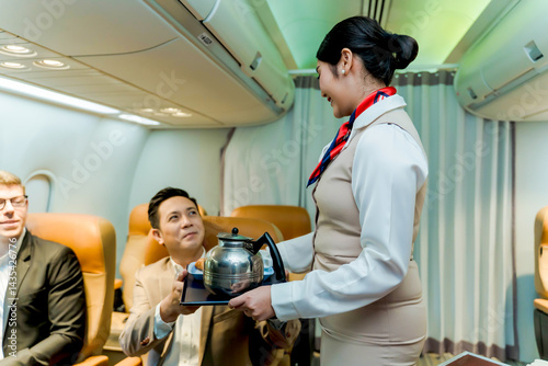 Smiling flight attendant serving coffee and breakfast to a businessman in premium airplane cabin, showcasing in-flight service and professional hospitality onboard