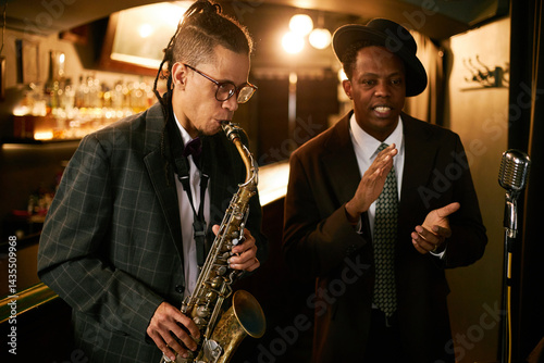 Canvas Print Medium shot of multiethnic male musician playing melody on saxophone performing