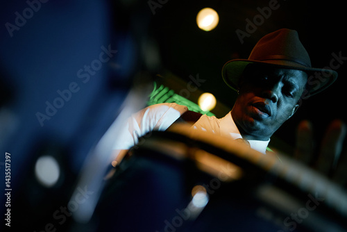 Canvas Print Dutch angle shot of concentrated Black male drummer wearing hat playing congas w