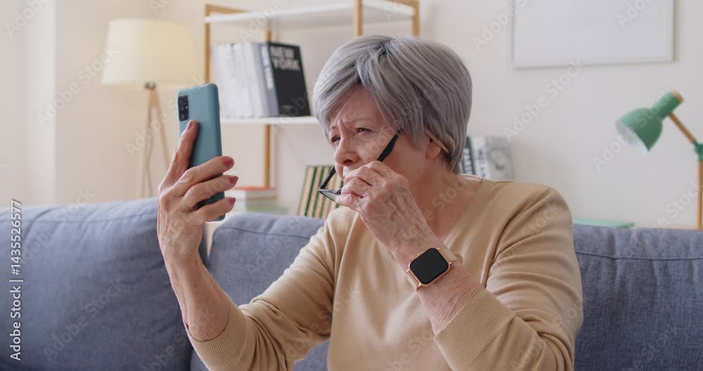 Senior woman bad sight problem, old lady in glasses difficult reading text message on mobile phone, browsing Internet, social media, using online shopping app, trying making video call at home