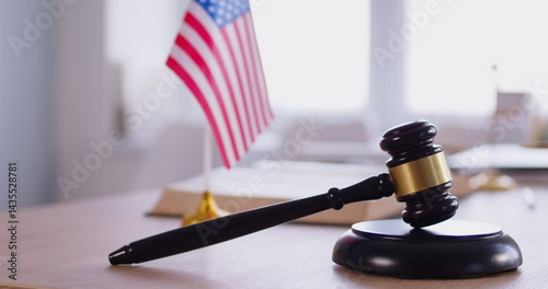 Wooden judge gavel against national USA flag. Justice and law in America. Judges workplace. Constitution, judgement, patriotism and legal system. Judge's hammer for attention and verdict. 