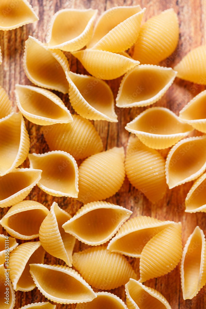 Raw uncooked dried Conchiglie shell pasta. Italian seashells pasta on wooden background. Raw uncooked dried Conchiglie shell pasta. Italian seashells pasta on wooden background.