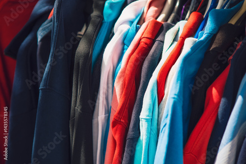 Obraz na płótnie Rack of colorful hoodies hang closely together, creating a vibrant display. Lighting highlights the fabric textures, suggesting a casual shopping or market setting w salonie