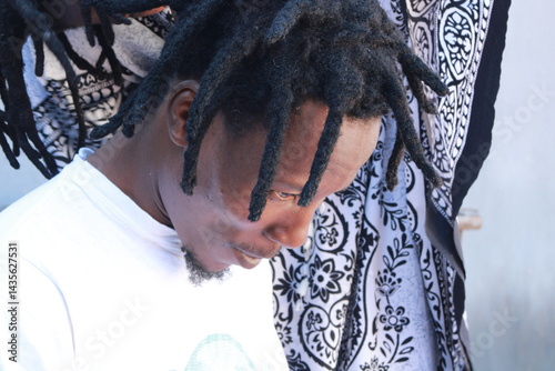 African Man with dreadlocks in a hair salon plaited by a young African lady