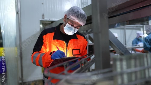 engineer in safety helmets and vests inspecting control systems inside a clean, industrial food processing plant while discussing findings on a digital tablet.